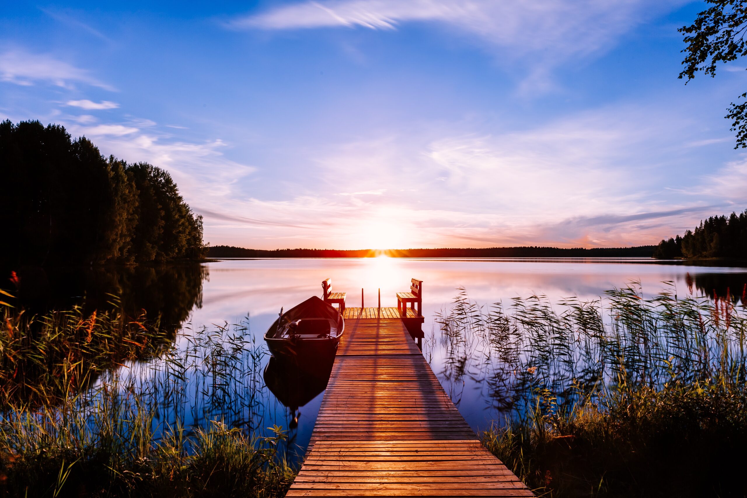 Wooden pier with fishing boat at sunset on a lake